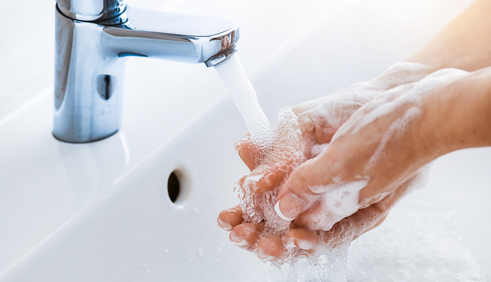 ผู้หญิงใช้สบู่และล้างมือใต้ก๊อกน้ำ รายละเอียดมือของสุขอนามัย